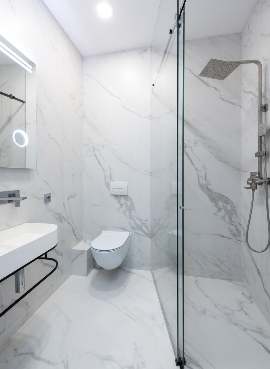 Clean white marble bathroom with glass shower and modern fixtures